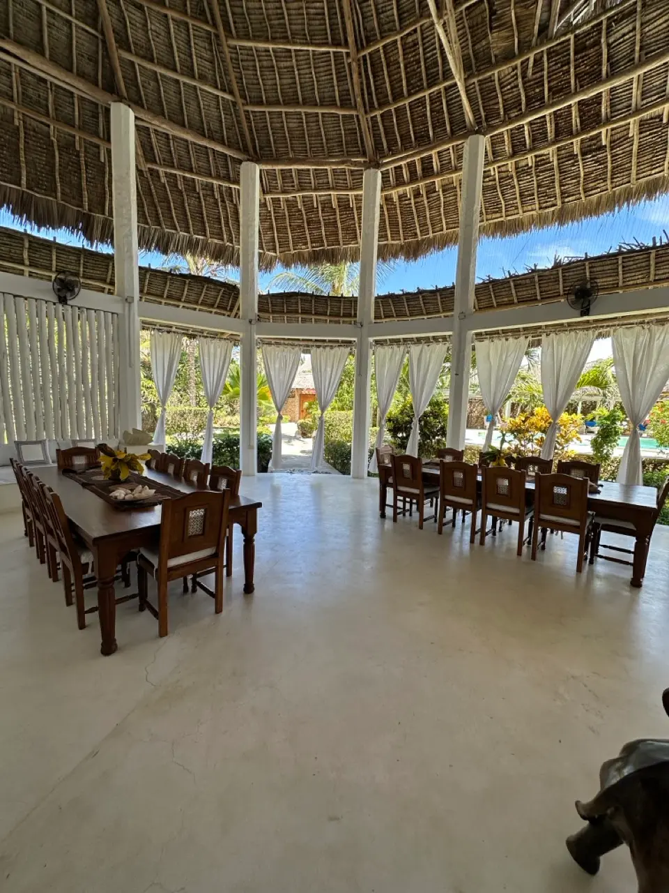 Veranda da pranzo con tetto in paglia e vista sul giardino tropicale